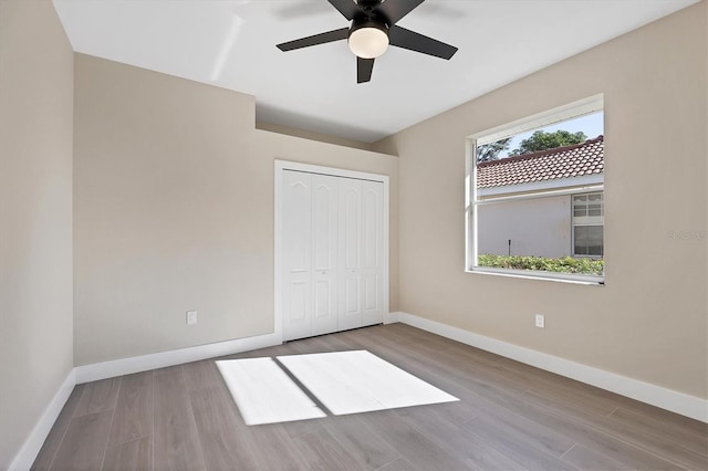 unfurnished bedroom with ceiling fan, light wood-type flooring, and a closet