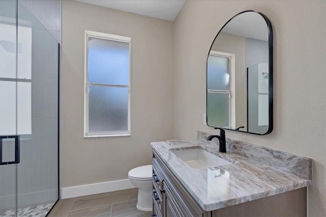 bathroom featuring wood-type flooring, vanity, a shower with shower door, and toilet