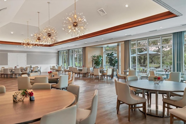 dining area featuring a chandelier, a high ceiling, a tray ceiling, and parquet floors