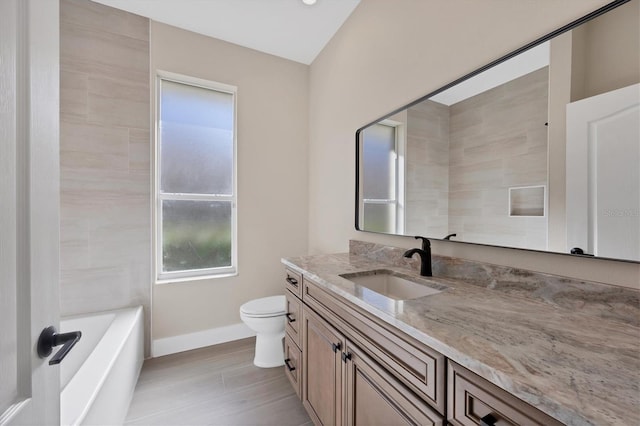 bathroom with a bathing tub, hardwood / wood-style flooring, vanity, and toilet