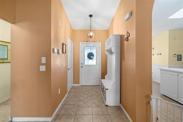 entryway featuring light tile patterned floors and lofted ceiling with skylight