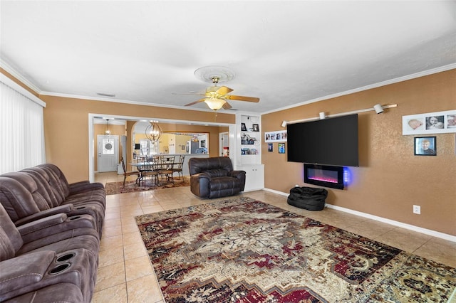 tiled living room featuring built in shelves, ceiling fan with notable chandelier, and ornamental molding