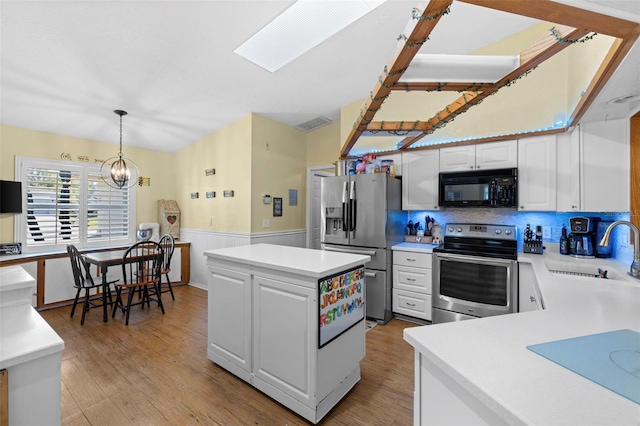 kitchen with a center island, white cabinets, sink, decorative light fixtures, and stainless steel appliances