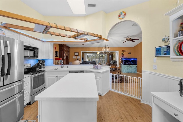 kitchen with kitchen peninsula, appliances with stainless steel finishes, light hardwood / wood-style floors, and a kitchen island