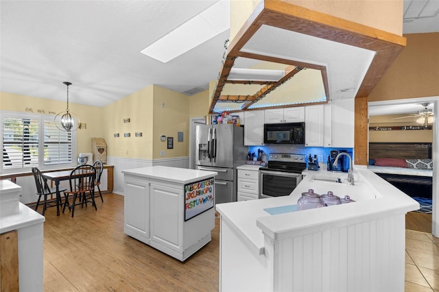 kitchen featuring appliances with stainless steel finishes, sink, light hardwood / wood-style flooring, a center island, and white cabinetry