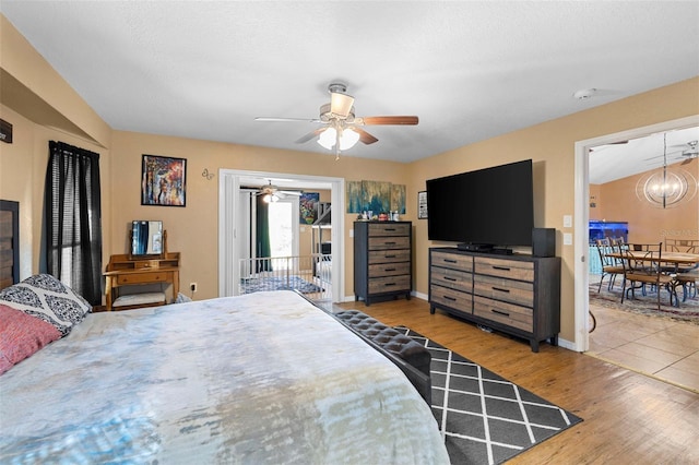 bedroom with wood-type flooring and ceiling fan with notable chandelier