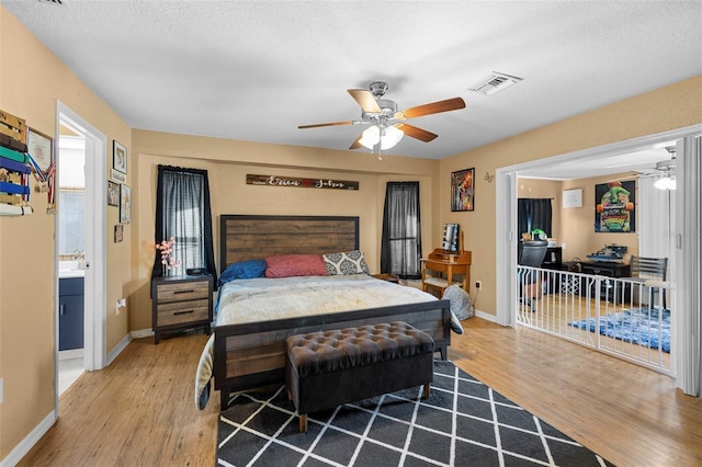 bedroom with a textured ceiling, hardwood / wood-style flooring, and ceiling fan