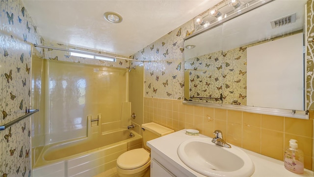 full bathroom featuring vanity, shower / bath combination, toilet, and tile walls