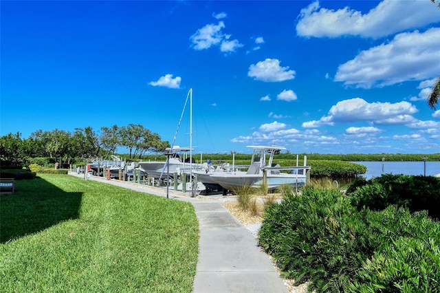 surrounding community with a water view, a yard, and a dock