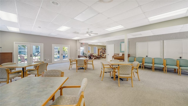 carpeted dining area with french doors, a drop ceiling, and ceiling fan