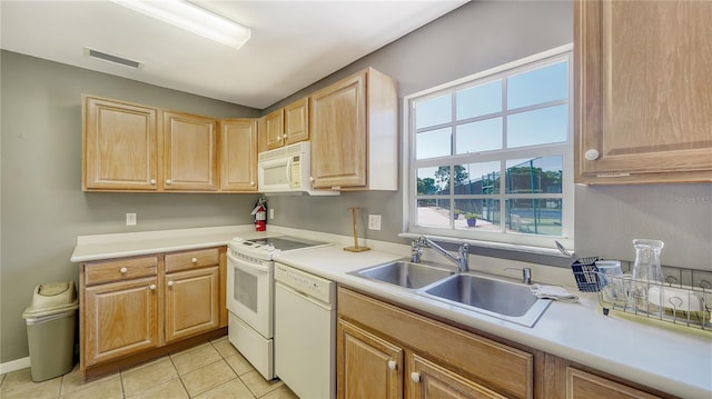 kitchen featuring light tile patterned flooring, light brown cabinetry, white appliances, and sink