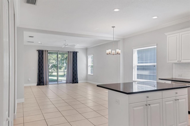 kitchen featuring backsplash, ornamental molding, ceiling fan with notable chandelier, white cabinets, and light tile patterned flooring