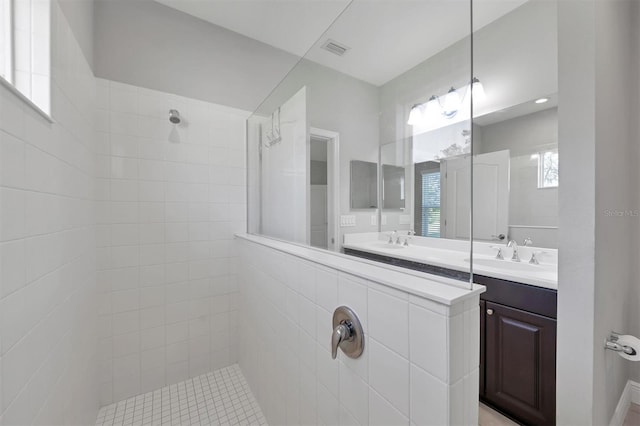 bathroom with a tile shower and vanity