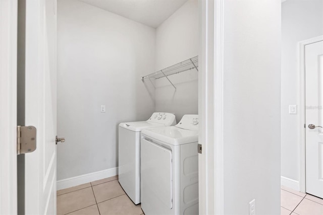 clothes washing area with washing machine and dryer and light tile patterned floors