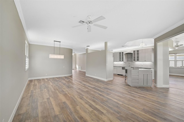 unfurnished living room with ceiling fan, hardwood / wood-style floors, sink, and ornamental molding