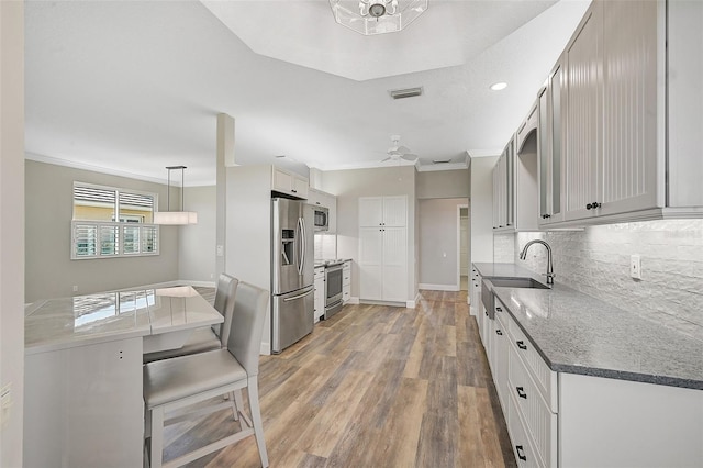 kitchen featuring decorative light fixtures, stainless steel appliances, hardwood / wood-style flooring, and crown molding