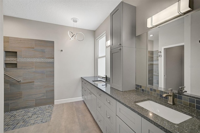 bathroom featuring vanity, tiled shower, a textured ceiling, and an inviting chandelier