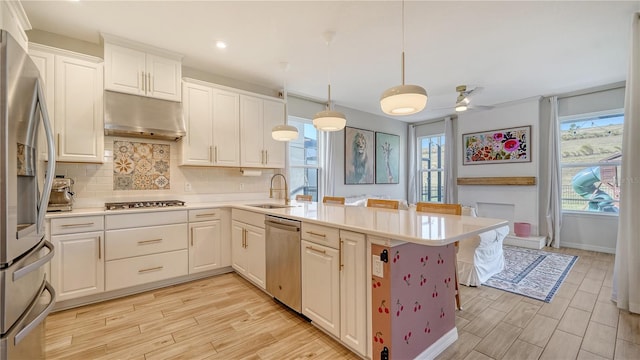 kitchen featuring appliances with stainless steel finishes, decorative light fixtures, white cabinetry, sink, and kitchen peninsula