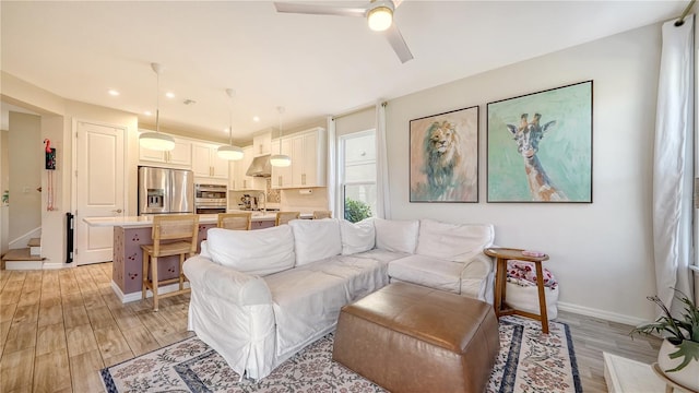 living room featuring sink, light hardwood / wood-style flooring, and ceiling fan