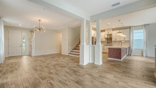 interior space featuring sink, a notable chandelier, and light wood-type flooring