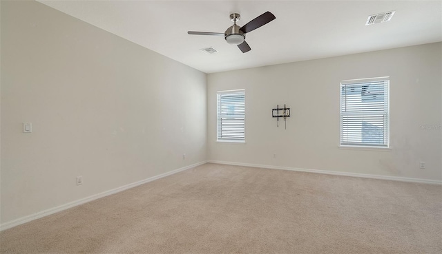 unfurnished room with a healthy amount of sunlight, light carpet, and ceiling fan