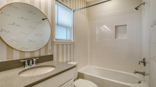 full bathroom featuring tiled shower / bath combo, vanity, and toilet