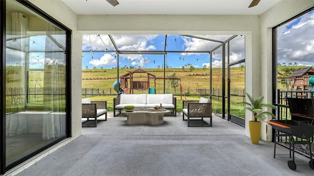 sunroom with ceiling fan and a rural view