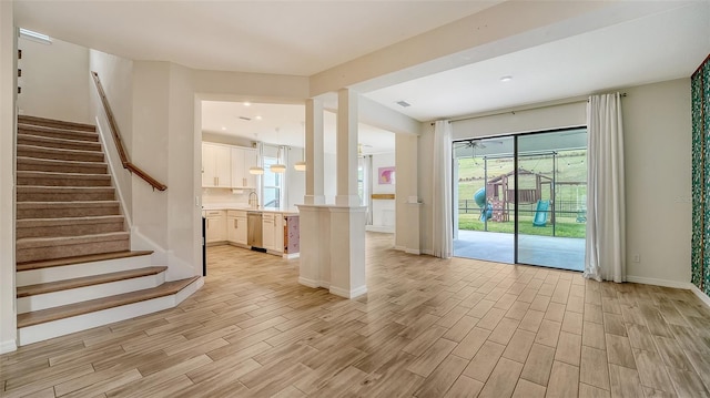 5548 Summit Gln, Bradenton, FL 34203 - unfurnished living room featuring light wood-type flooring, healthy amount of natural light, stairway, decorative columns, and recessed lighting