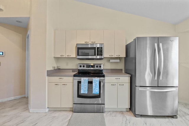 kitchen with cream cabinets, lofted ceiling, and appliances with stainless steel finishes