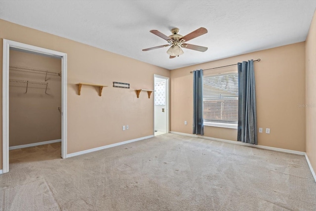 unfurnished bedroom with carpet floors, a closet, a spacious closet, and ceiling fan