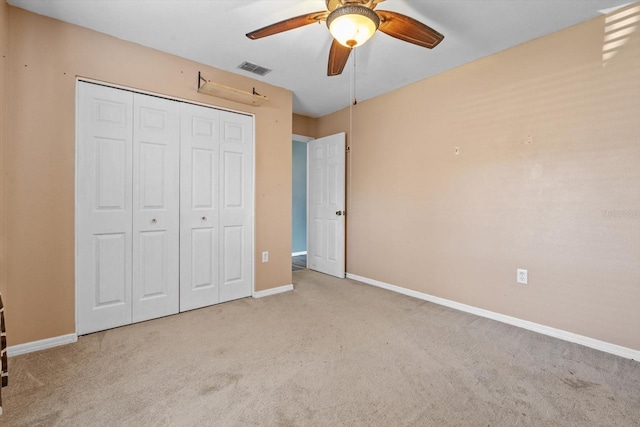 unfurnished bedroom with a closet, light colored carpet, and ceiling fan