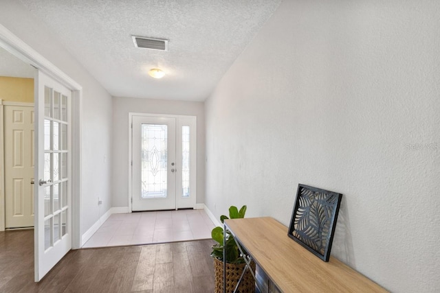 interior space with french doors, light hardwood / wood-style floors, and a textured ceiling