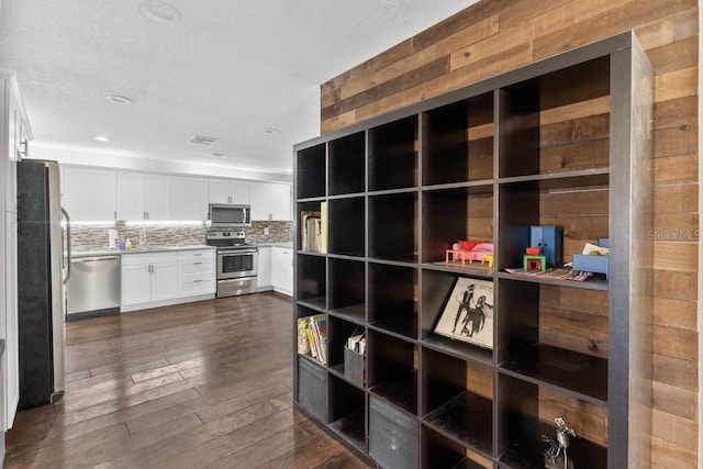 kitchen with white cabinetry, dark wood-type flooring, tasteful backsplash, a textured ceiling, and appliances with stainless steel finishes