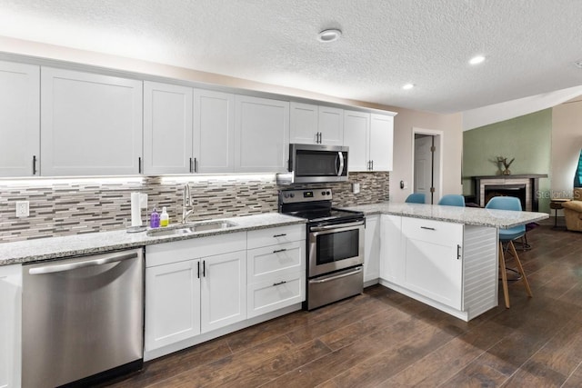 kitchen with dark hardwood / wood-style flooring, white cabinetry, sink, and appliances with stainless steel finishes