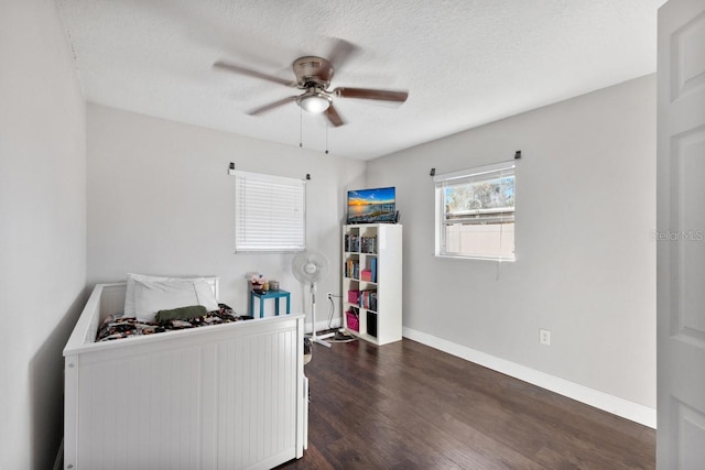 bedroom with ceiling fan, dark wood-type flooring, and a textured ceiling