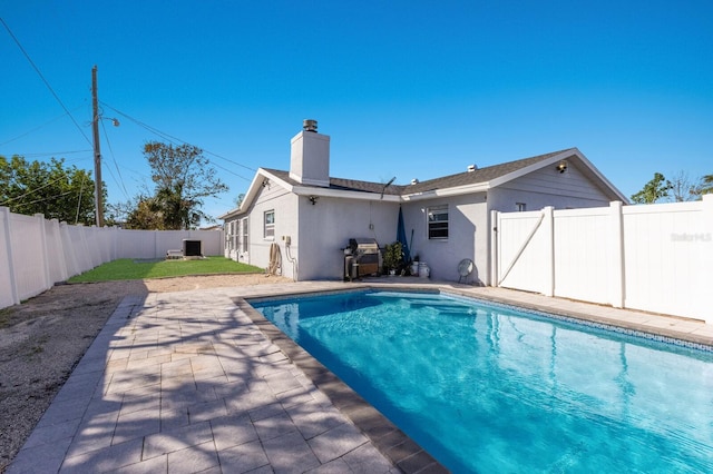 view of swimming pool featuring a grill and a patio