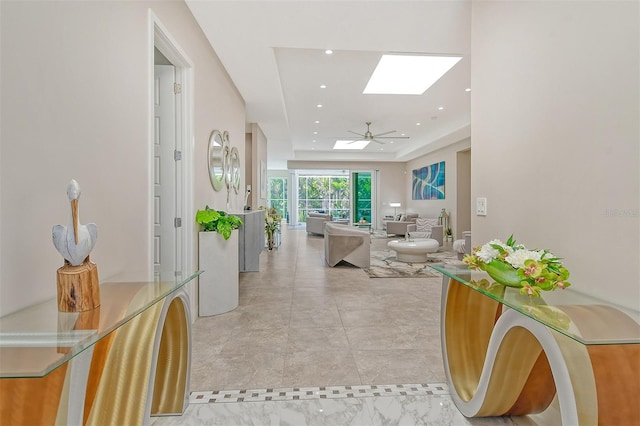 hall featuring a skylight and a tray ceiling