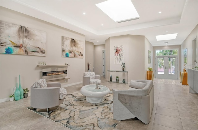 tiled living room with a tray ceiling, a skylight, and french doors