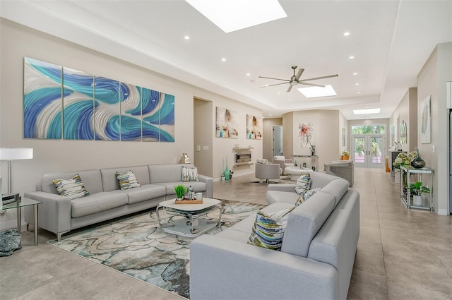 living room featuring french doors, a skylight, a raised ceiling, and ceiling fan