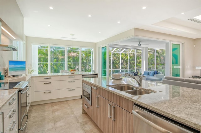 kitchen with light stone counters, ceiling fan, sink, and stainless steel appliances