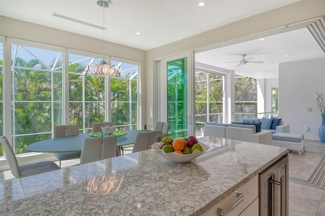 sunroom / solarium featuring wine cooler, ceiling fan with notable chandelier, and a wealth of natural light