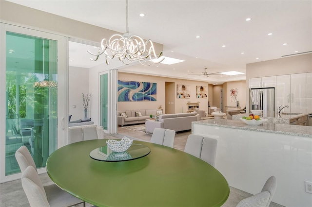 dining area with ceiling fan with notable chandelier and sink