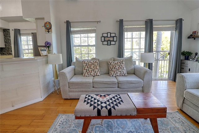 living room featuring lofted ceiling, light wood-type flooring, and a wealth of natural light