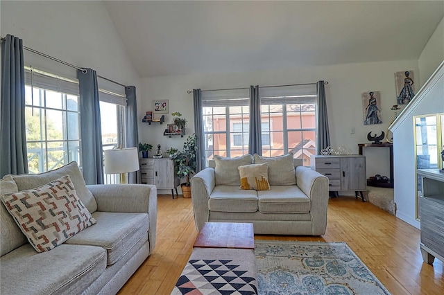 living room with plenty of natural light, light hardwood / wood-style floors, and lofted ceiling