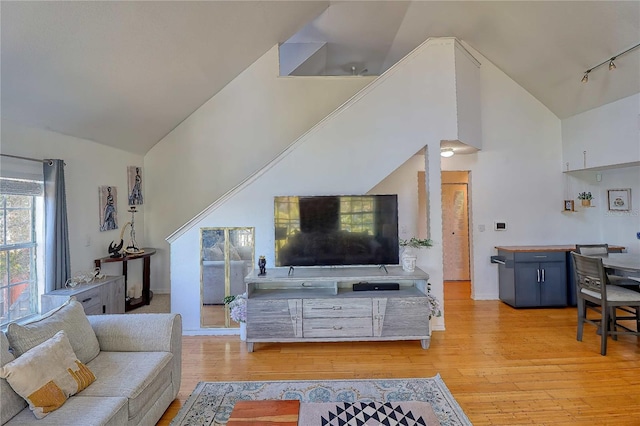 living room featuring light hardwood / wood-style flooring, high vaulted ceiling, and rail lighting