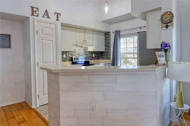 kitchen featuring stainless steel electric stove, decorative backsplash, kitchen peninsula, and light hardwood / wood-style flooring