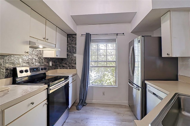 kitchen with backsplash, white cabinetry, stainless steel appliances, and light wood-type flooring