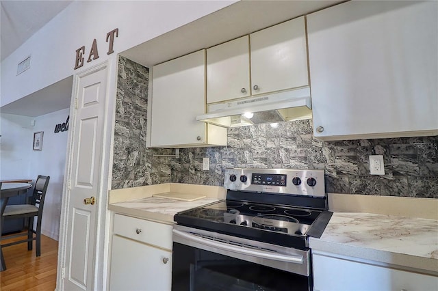 kitchen featuring hardwood / wood-style flooring, white cabinets, stainless steel electric range oven, and backsplash