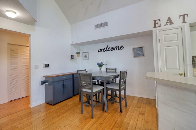 dining area with light hardwood / wood-style floors and lofted ceiling