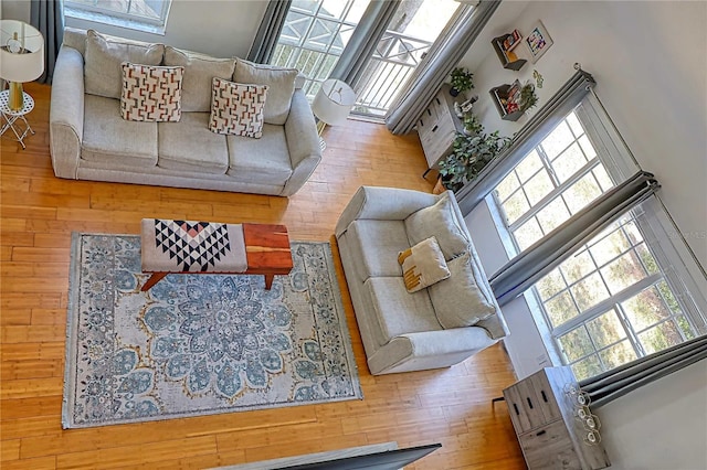 living room with light hardwood / wood-style floors and a towering ceiling